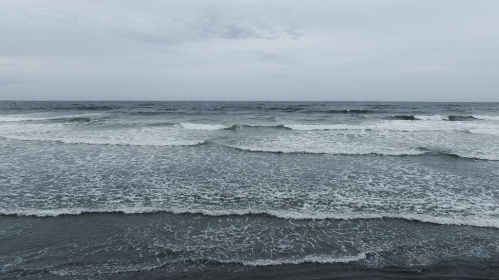 Free Image of Wave patterns on the ocean under a cloudy sky 
