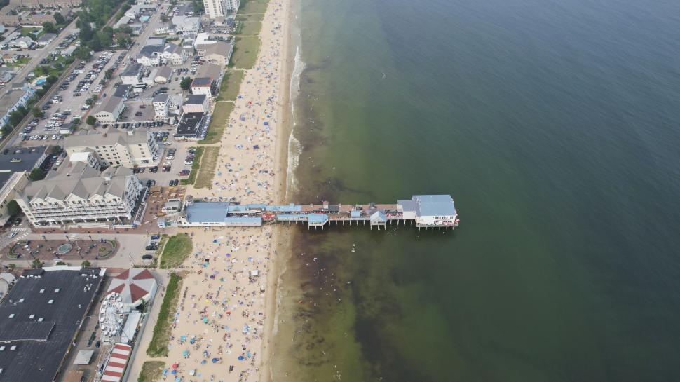 Free Image of Crowded beach with pier extending into the ocean 