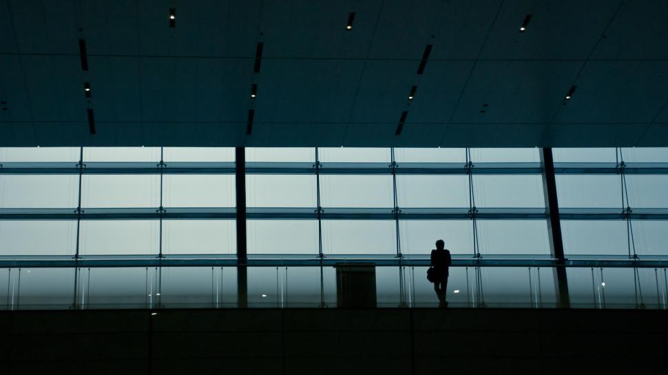 Free Image of Silhouette of person standing by large airport window 