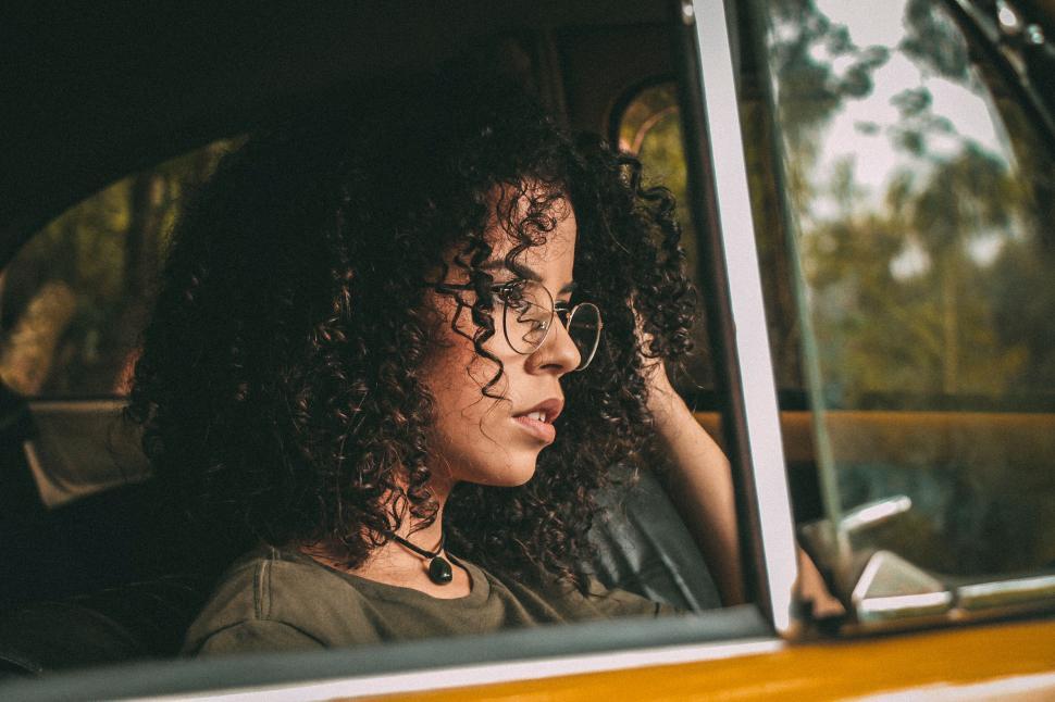 Free Image of Person with curly hair seen through car window glass. 