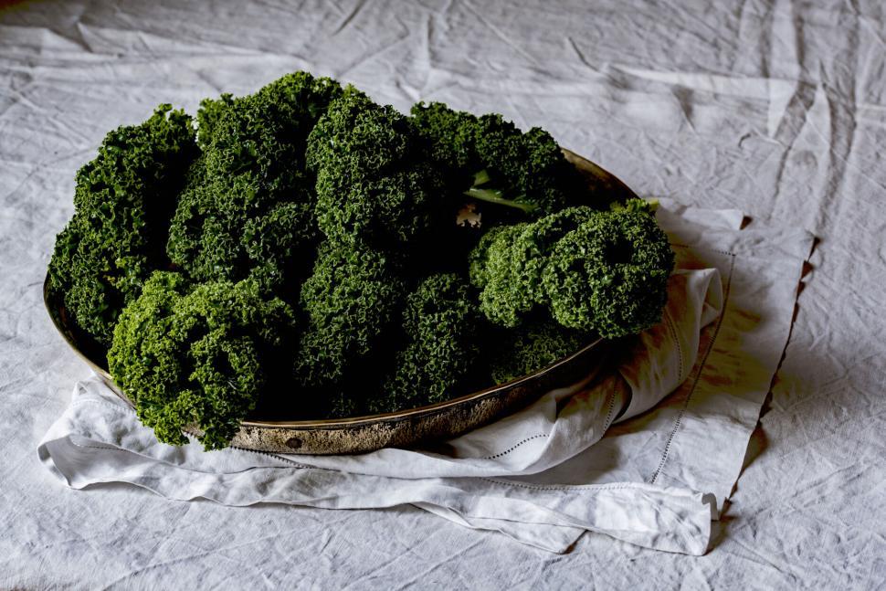 Free Image of Tray of fresh kale displayed on a white fabric cloth 