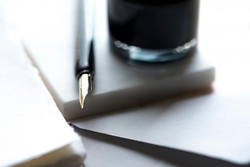 Free Image of Close-up of pen with ink bottle on white papers 
