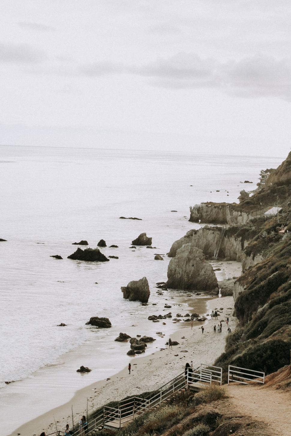 Free Image of Rocky ocean shoreline with cliffs under a cloudy sky. 