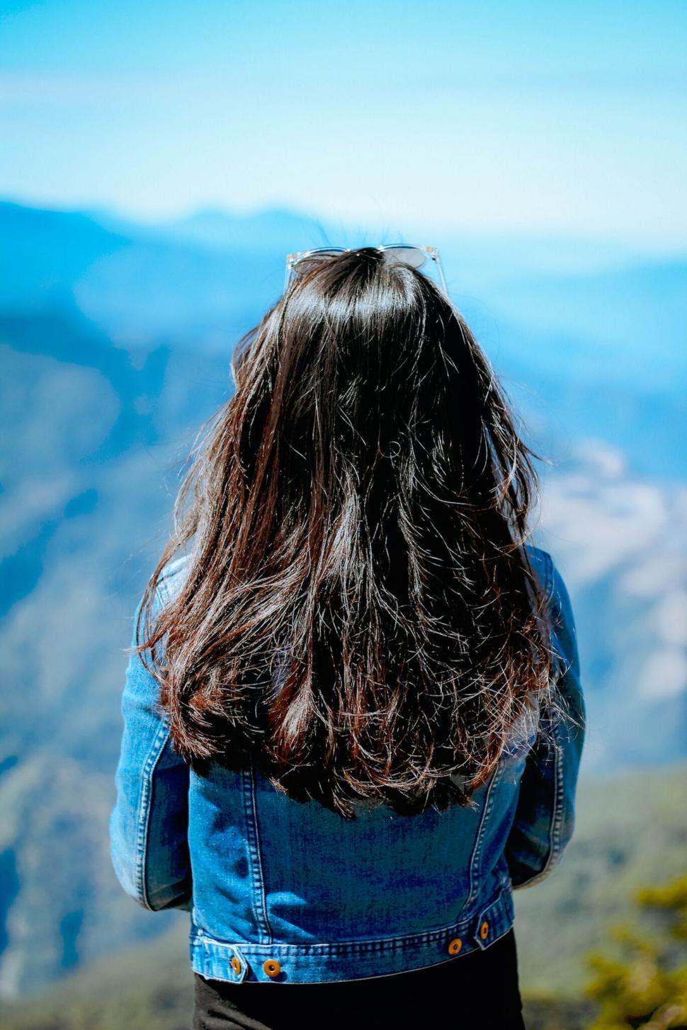 Free Image of A woman with long hair in a denim jacket at lookout. 