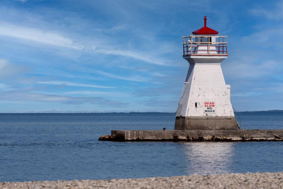 Free Image of Lighthouse by the sea on a clear sunny day. 