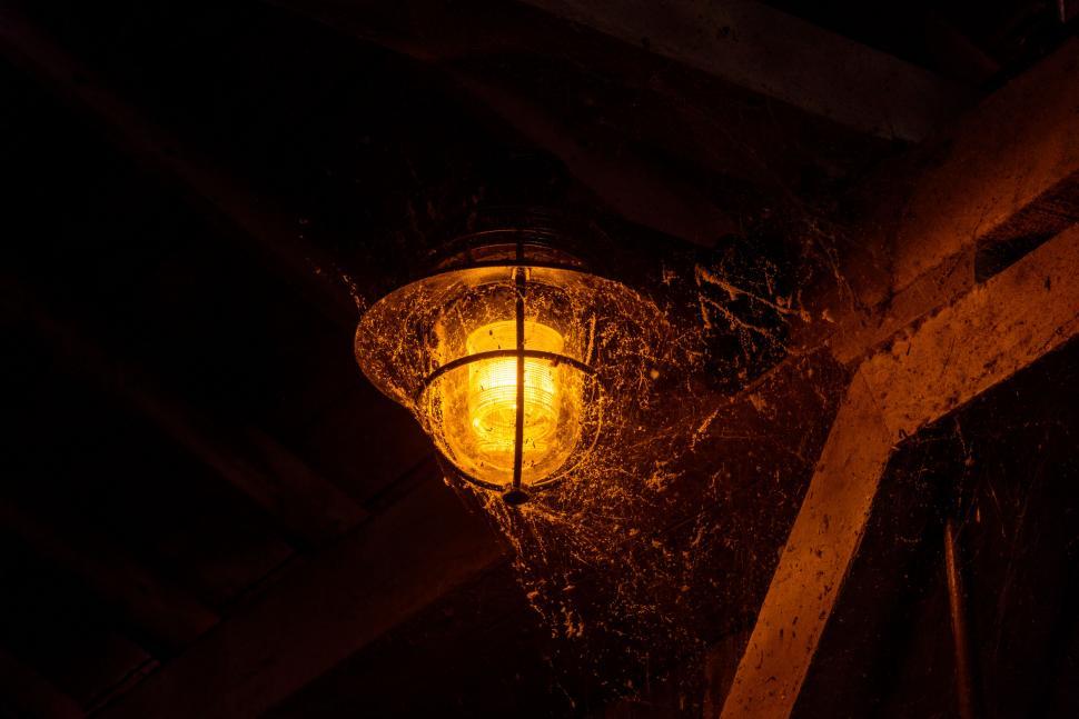 Free Image of Old light in an attic with cobwebs glowing warm amber 
