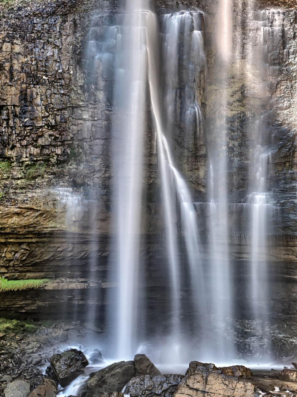 Free Image of Elegant waterfall cascading down a rocky cliff face 