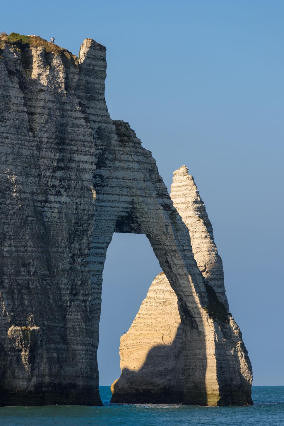 Free Image of Stone arch in sea with clear blue sky background. 