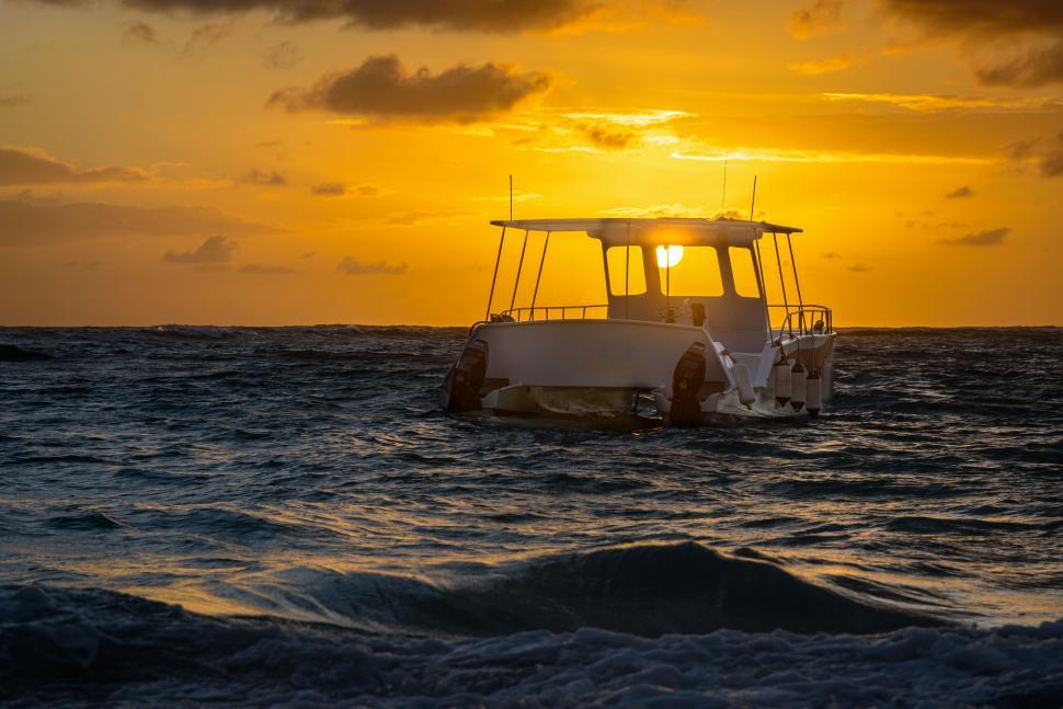 Free Image of A boat floating on the ocean waters during sunset time. 