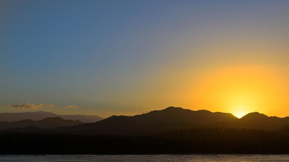 Free Image of Scenic sunrise over distant mountains and calm waters. 