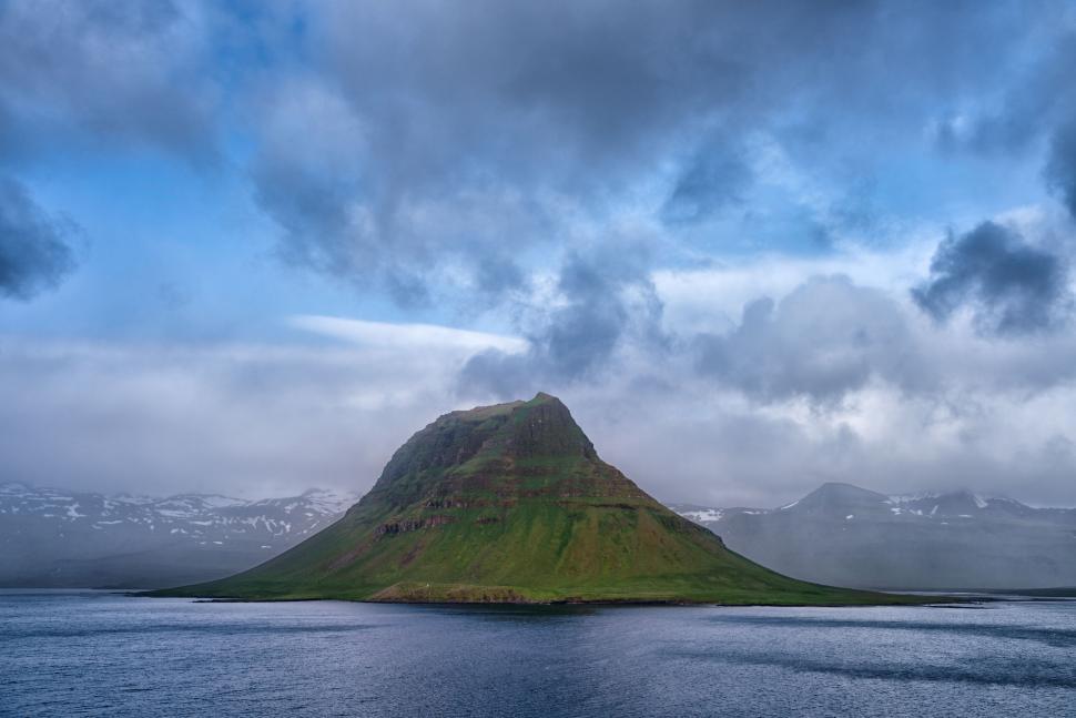 Free Image of Mountain island under a partially cloudy sky. 
