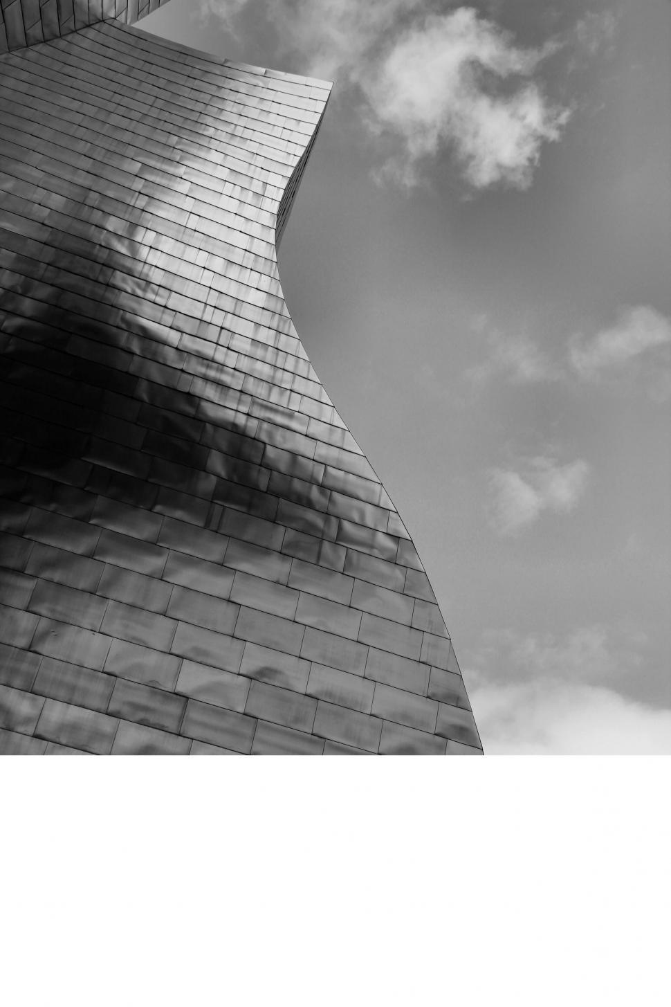 Free Image of Curved Metal Architecture with Cloudy Sky in Background 
