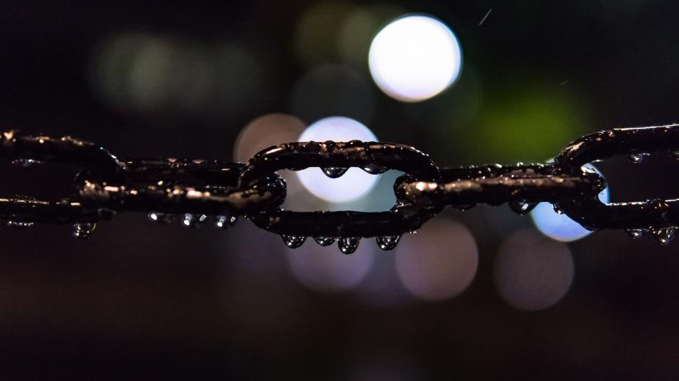 Free Image of Close-up of a wet chain with blurred lights in background 