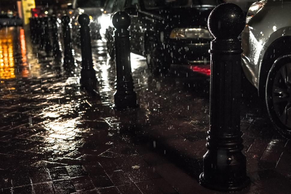 Free Image of Rainy night street with parked cars and wet pavement. 
