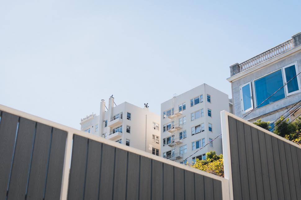 Free Image of Modern apartment buildings viewed from behind a fence. 