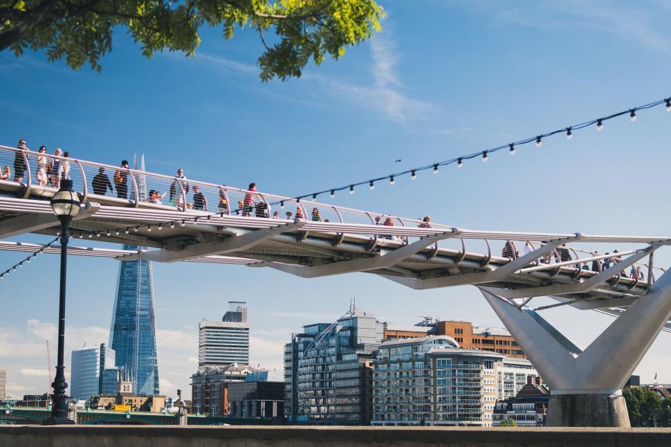 Free Image of People walking on a modern bridge with city skyline behind. 