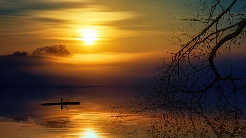 Free Image of Solitary canoe on still lake with misty sunrise background. 