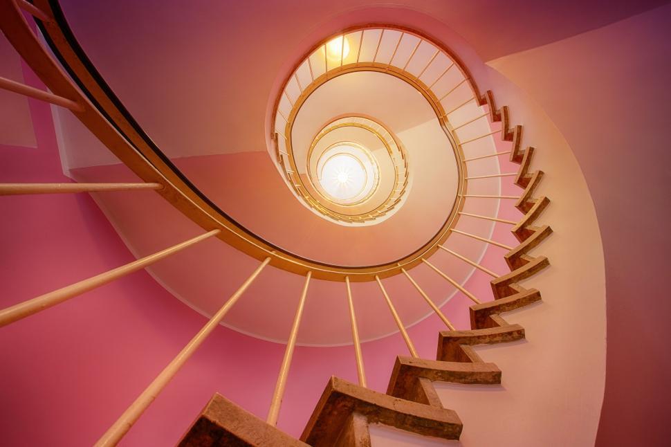 Free Image of Spiral staircase lit upward with warm glowing light 