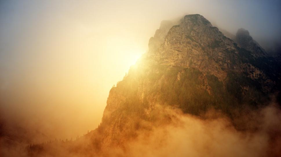 Free Image of Misty mountain peak illuminated by gentle sunlight. 
