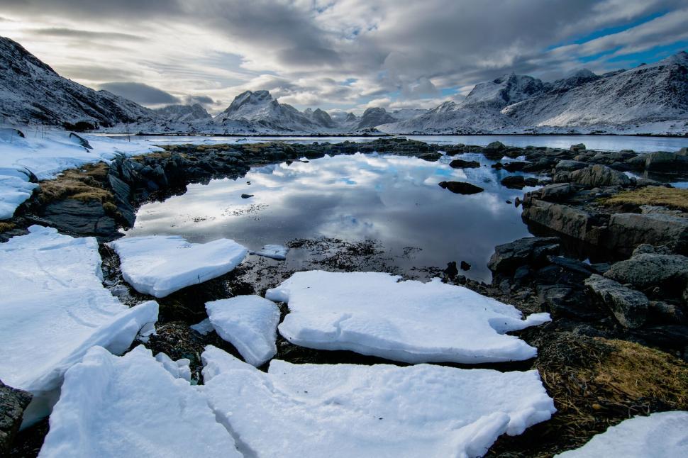 Free Image of Frozen landscape with icy lake and snowy mountains backdrop 