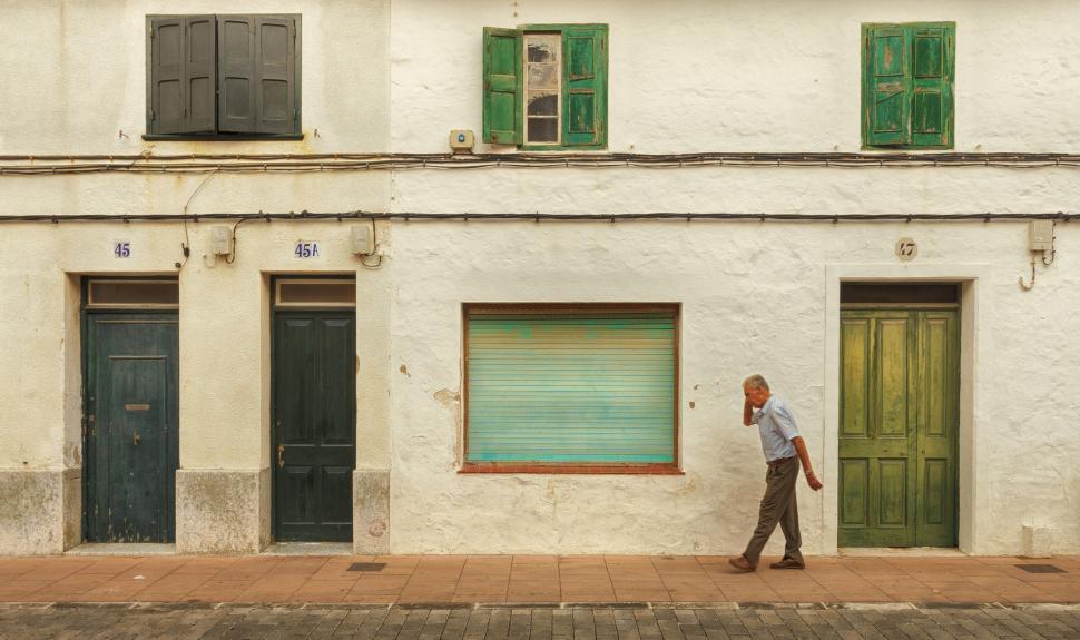 Free Image of Man walking past a row of unique, colorful doors. 