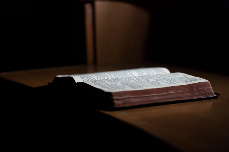 Free Image of Open book illuminated by a single light in darkness. 