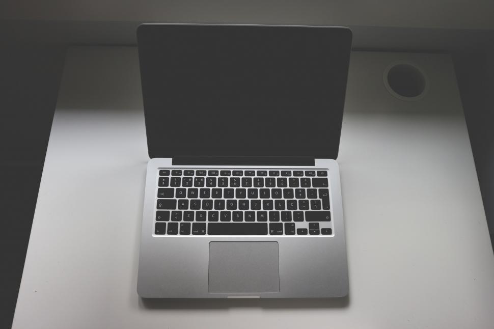 Free Image of Open laptop on a white table in a minimalistic setting 