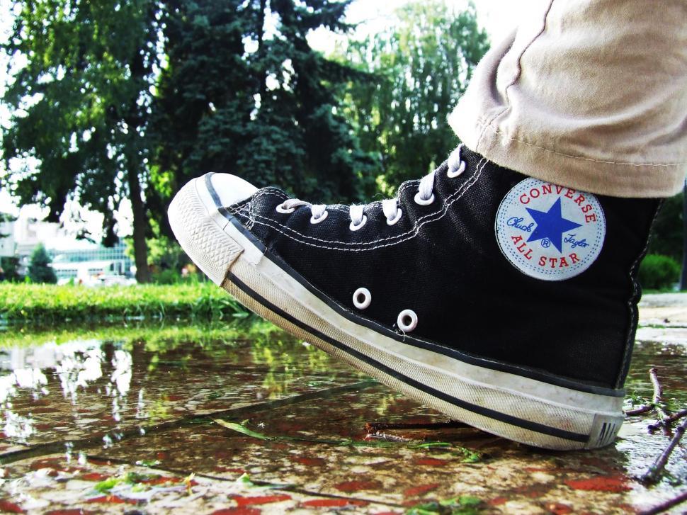 Free Image of Person Wearing Black Converse Shoes Standing in Puddle 