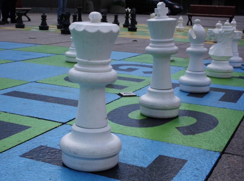 Free Image of Group of White Chess Pieces on Blue and Green Floor 