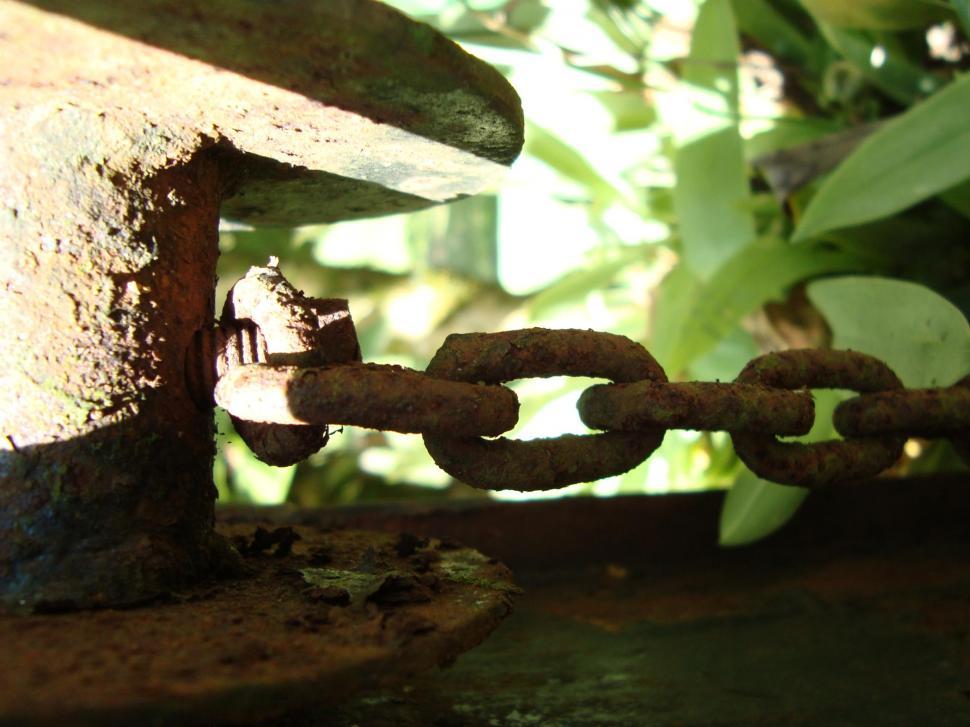 Free Image of Rusted Metal Chain With Birdhouse in Background 