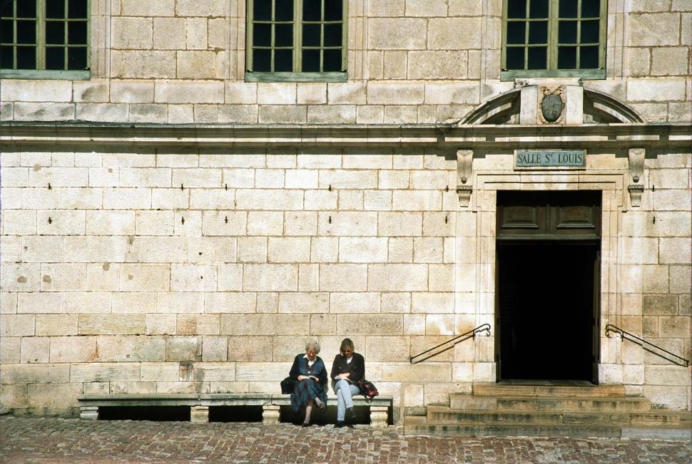 Free Image of france french women sitting old entryway entrance doorway stone buildings courtyard historic Beaune Hotel-Dieu Burgundy travel europe european stonework 