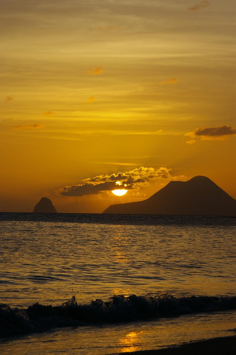 Free Image of Sun Setting Over Ocean With Mountains in Distance 