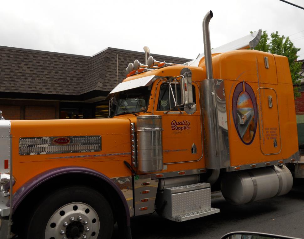 Free Image of Large Orange Truck Parked in Front of House 
