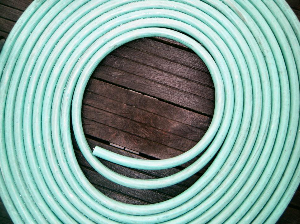 Free Image of Coil of rubber water hose lying on a deck - green 