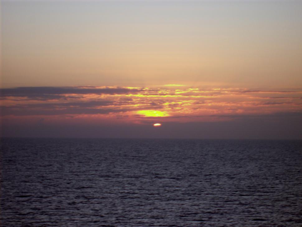 Free Image of Fantastic ocean sunset  through distant clouds 
