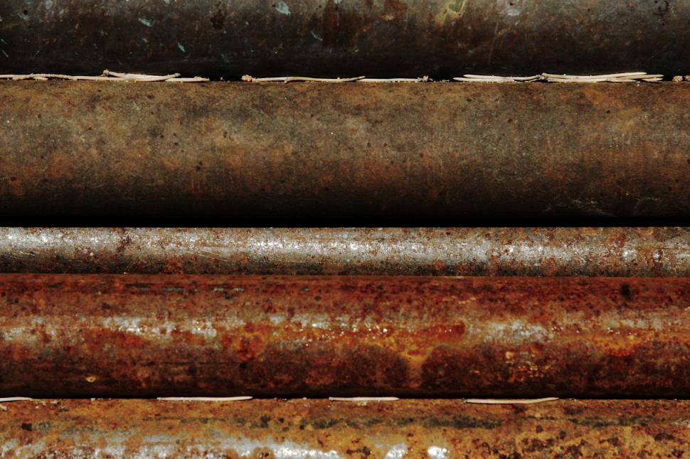 Free Image of A Pile of Rusty Pipes Stacked on Top of Each Other 