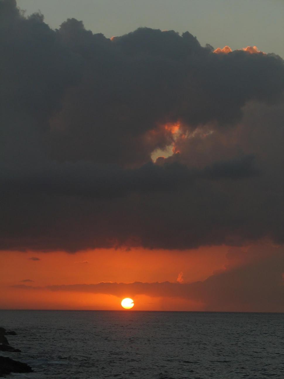 Free Image of Sun Setting Over Ocean on Cloudy Day 