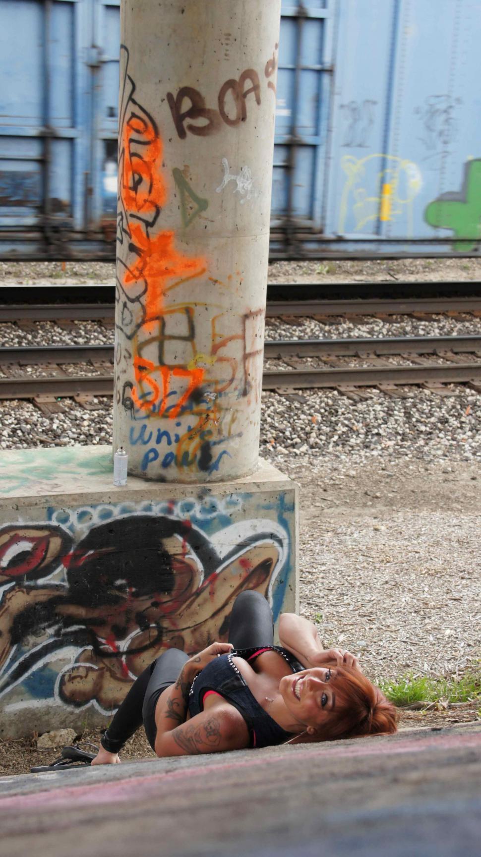 Free Image of Woman with Tattoos Poses with Graffiti 