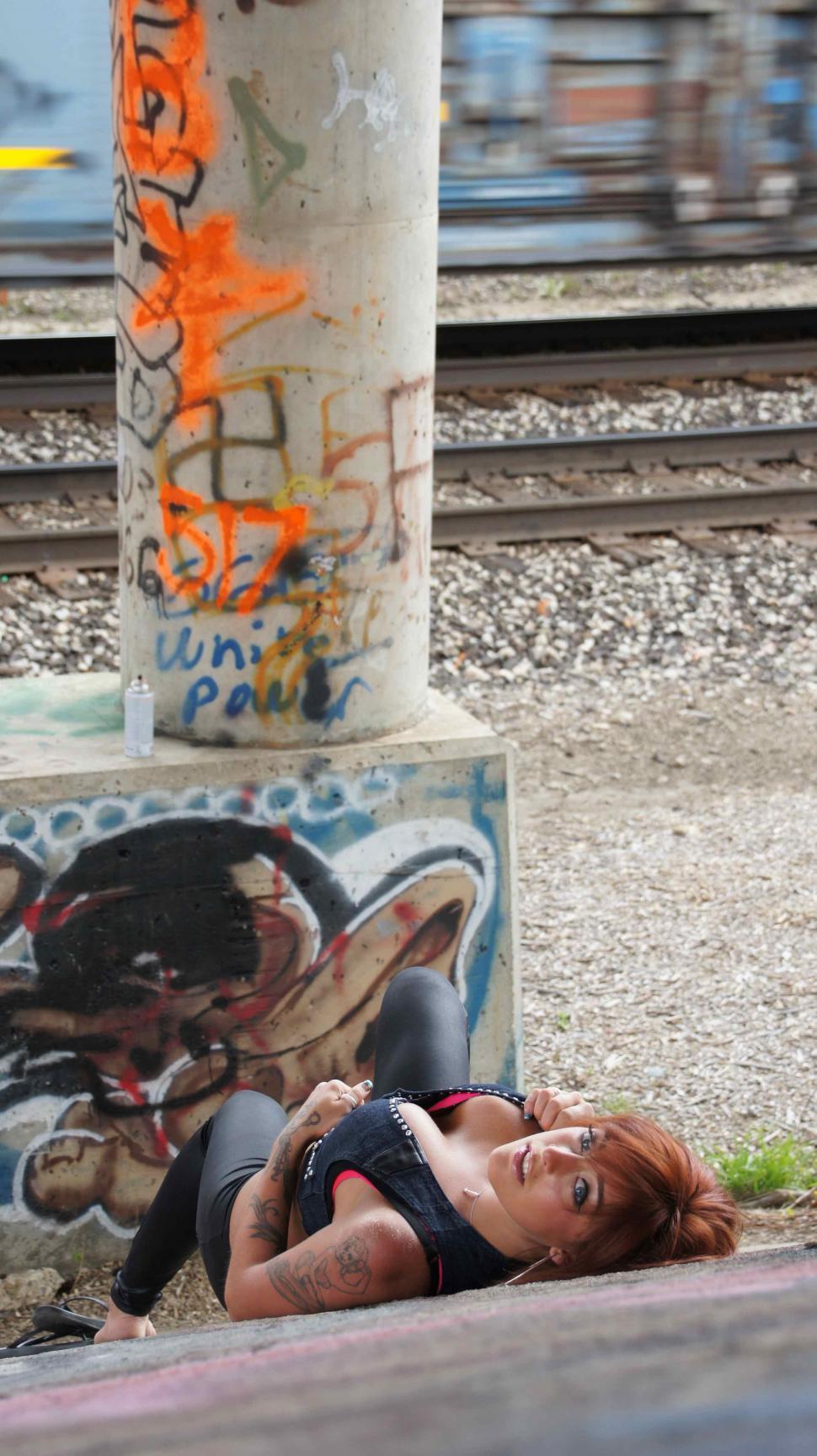 Free Image of Woman with Tattoos Poses with Graffiti 