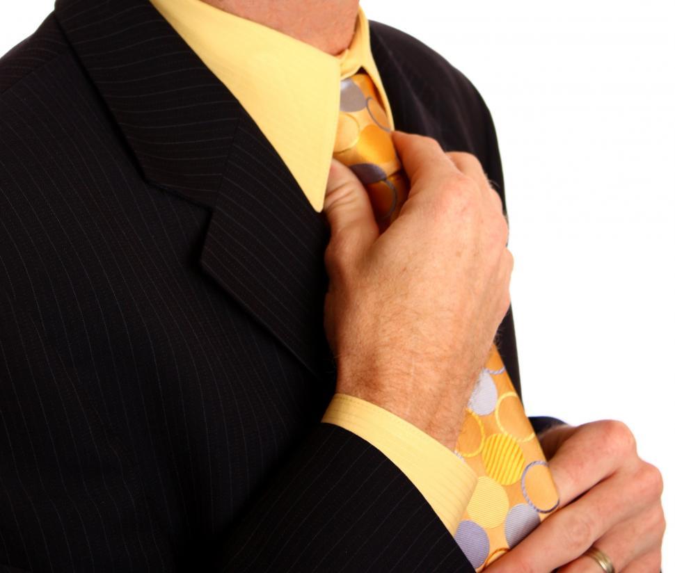 Free Image of A young businessman in a suit adjusting his tie 