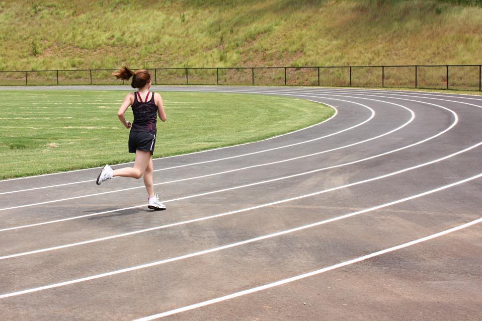 Free Image of A cute young girl running on a track field 