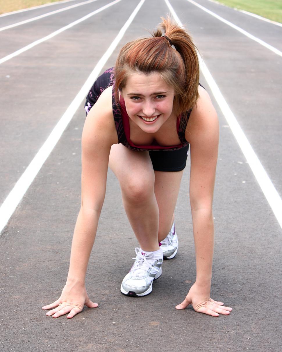 Download Free Stock Photo of A cute young girl on a track field preparing to race 