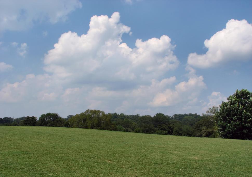 Free Image of A large grass field with a blue cloudy sky 