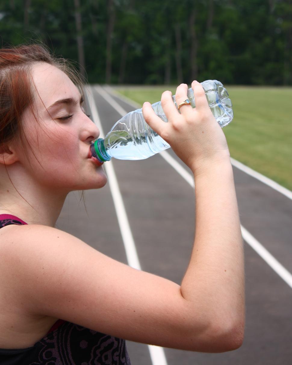 Free Image of A cute young girl drinking water on a track field 