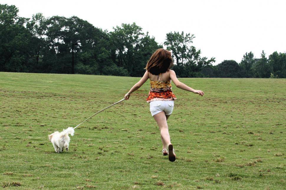 Free Image of A cute young girl running with her dog 
