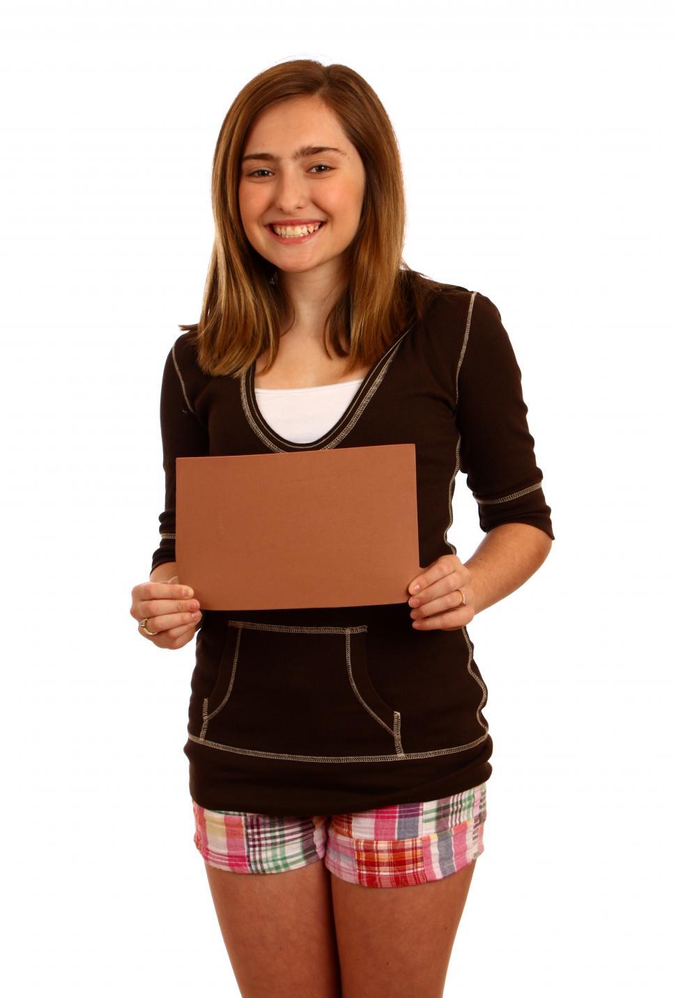 Free Image of A cute young girl posing with a blank brown sign 