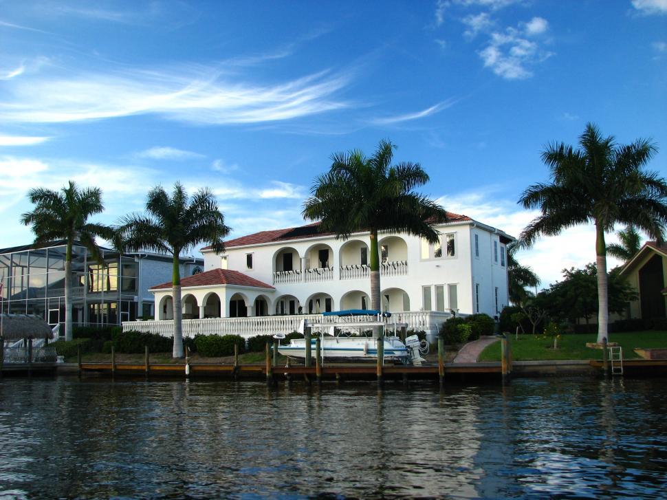 Free Image of A fancy house along the water with palm trees 