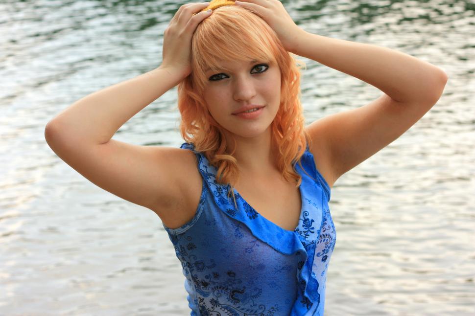 Free Image of A beautiful young woman posing by a lake 