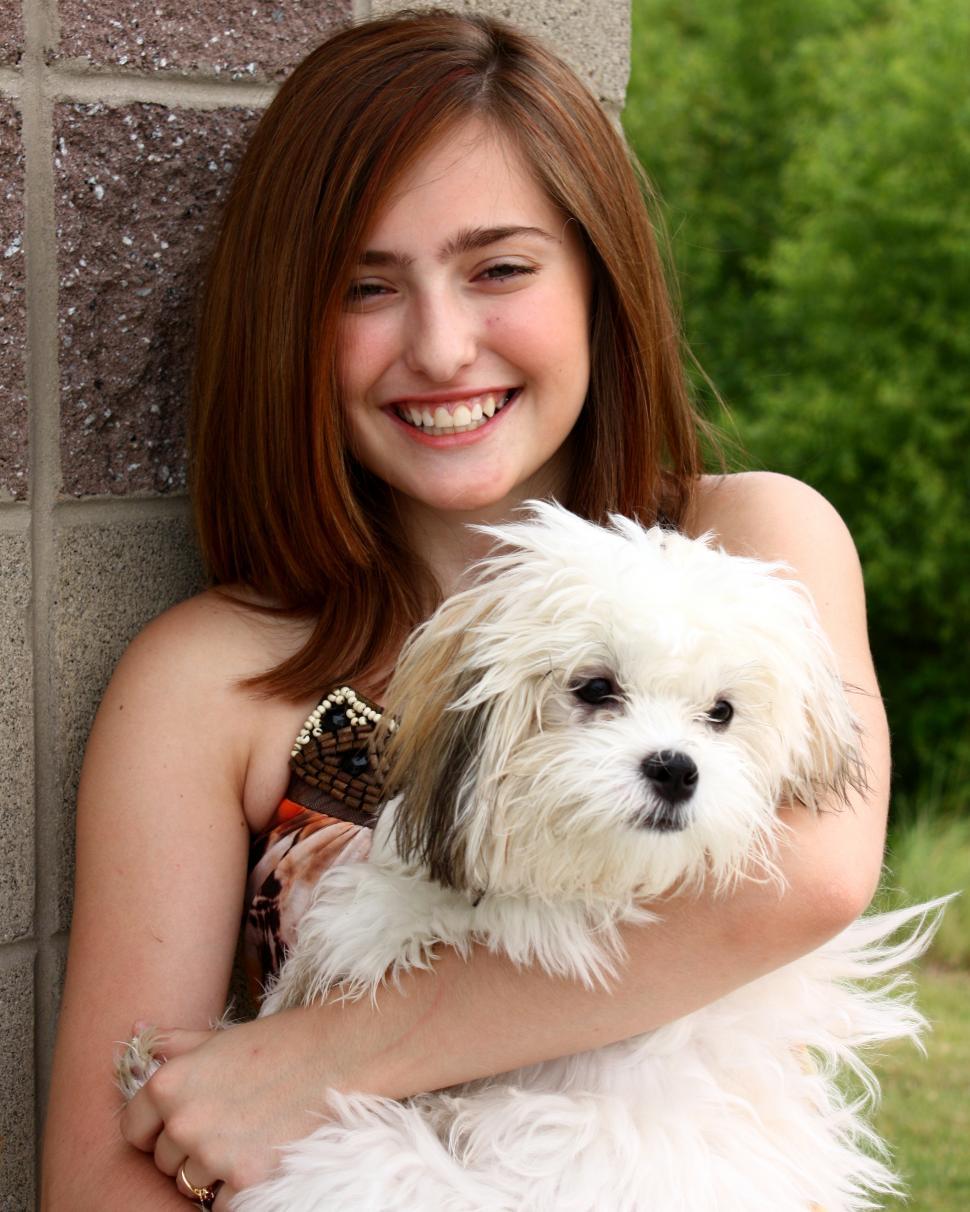 Free Image of A cute young girl posing with a small dog 