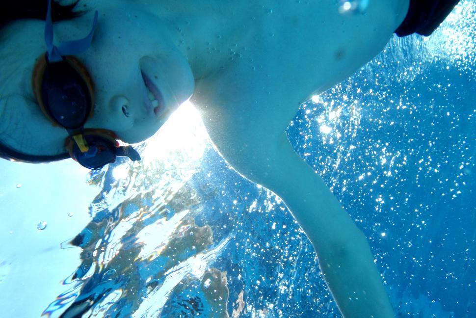 Free Image of Child swimming underwater smiling with goggles 
